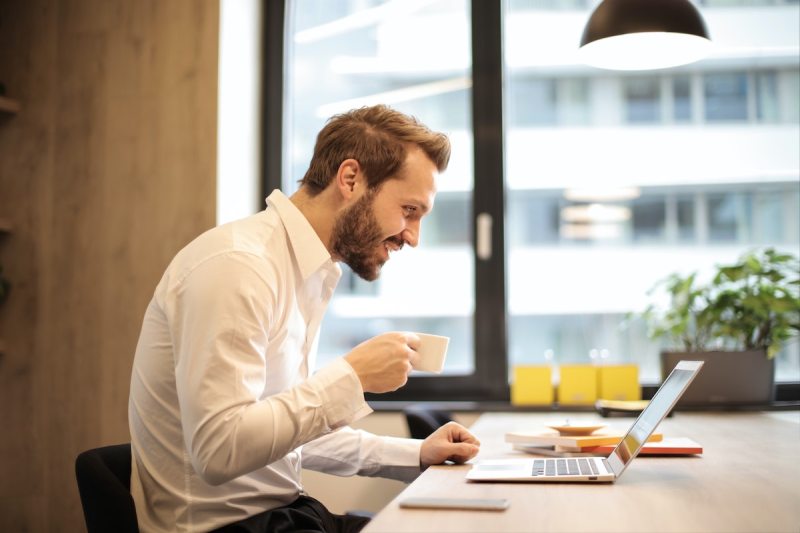 Happy man drinking coffee and smiling at work