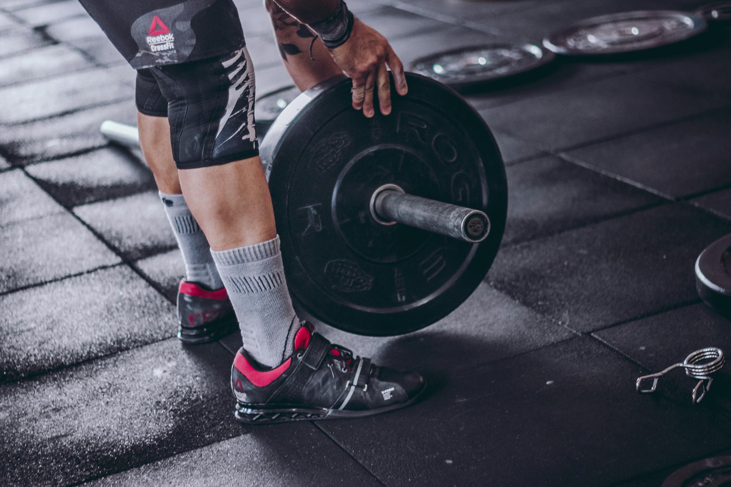 man holding barbell weight leaning down close up