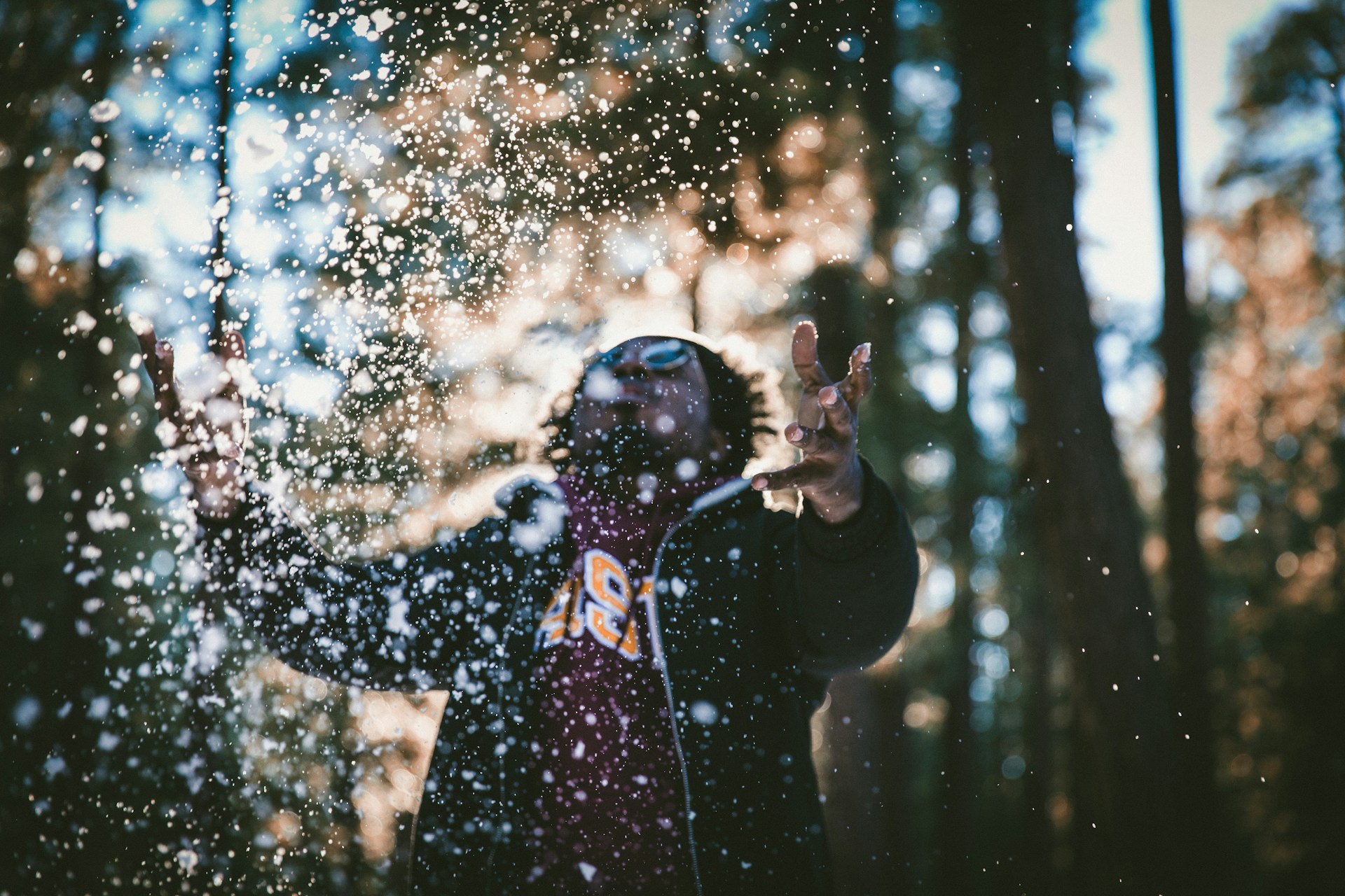 Man outside in the cold, throwing snow in the air.