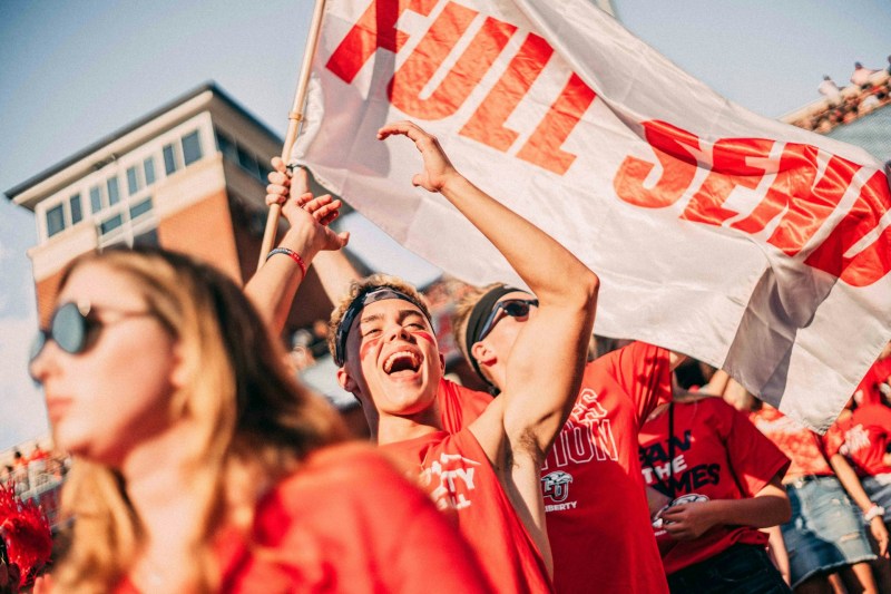 Young person cheering in the stands at a football game.